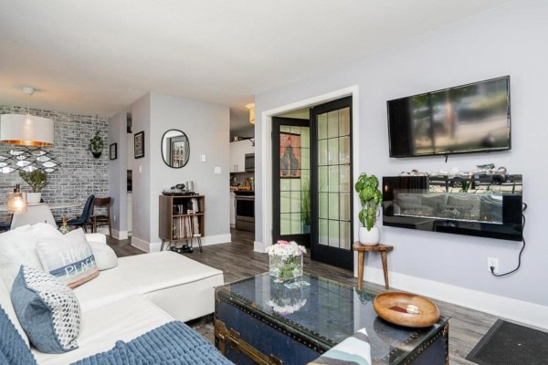 Spacious patio with concrete flooring, wicker furniture, potted plants, and a turquoise kayak. - 104 15991 Thrift Avenue, White Rock