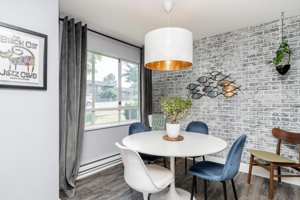 White kitchen with stainless steel appliances, grey countertops, and wood-look flooring. - 104 15991 Thrift Avenue, White Rock