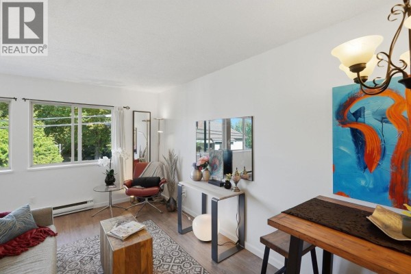 Living room with sofa, accent chair, console table, and large abstract art on the wall. - 104 3465 Glen Drive, Vancouver