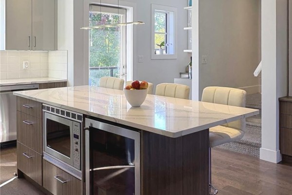 Kitchen island with microwave and wine fridge, with bar stools in a modern townhouse. - 104 3999 Cedar Hill Rd, Saanich