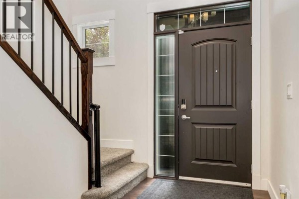 Interior view of the front entrance with a dark wood door and staircase. - 104 Auburn Shores Way Se, Calgary