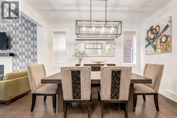 Formal dining room with a dark wood table, upholstered chairs, and decorative wall art. - 104 Auburn Shores Way Se, Calgary
