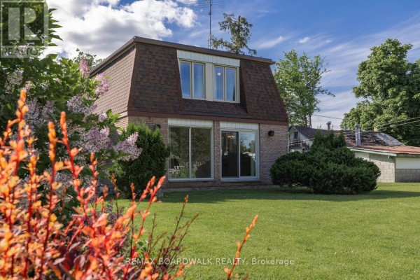 A two-story brick house with a mansard roof and large windows, seen from the front yard. - 104 Avenue 4a, Beckwith