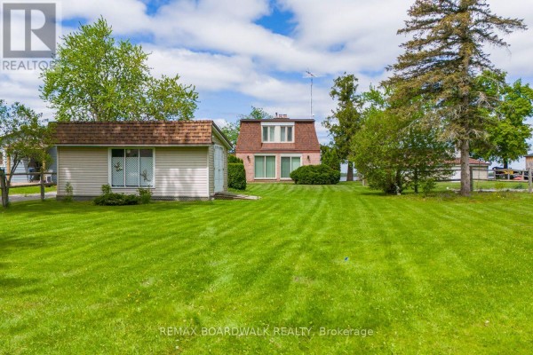 A wide view of the property showing a lawn, a detached garage, and the main house. - 104 Avenue 4a, Beckwith