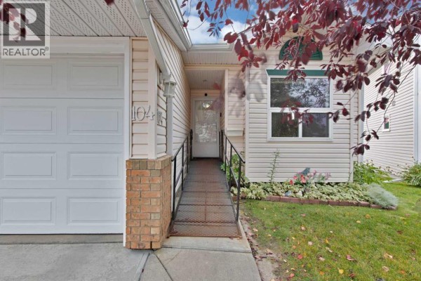 Front entryway of townhouse with a ramp, glass door, and adjacent window. - 104 Catalina Circle Ne, Calgary