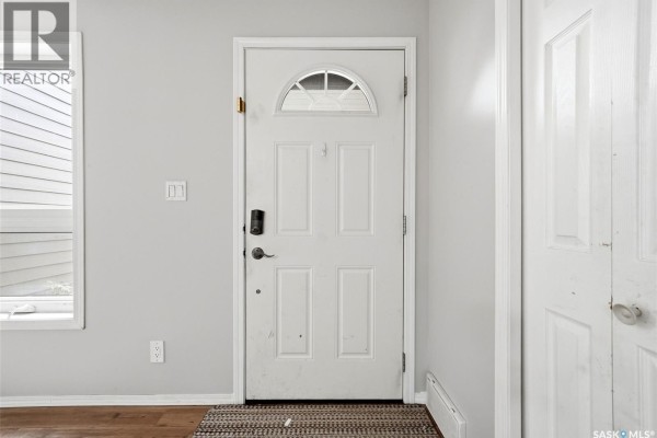 Interior view of a white front door with a arched window and a adjacent closet door. - 104 Cedar Meadow Drive, Regina