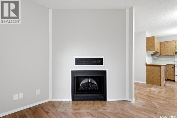 Close-up of a black gas fireplace with a brick surround. Wood cabinets are visible in the background. - 104 Cedar Meadow Drive, Regina