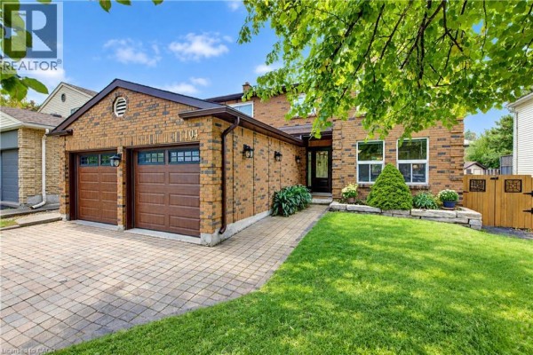 View of the house entrance with a paved walkway and double garage doors. - 104 Deerwood Crescent, Kitchener
