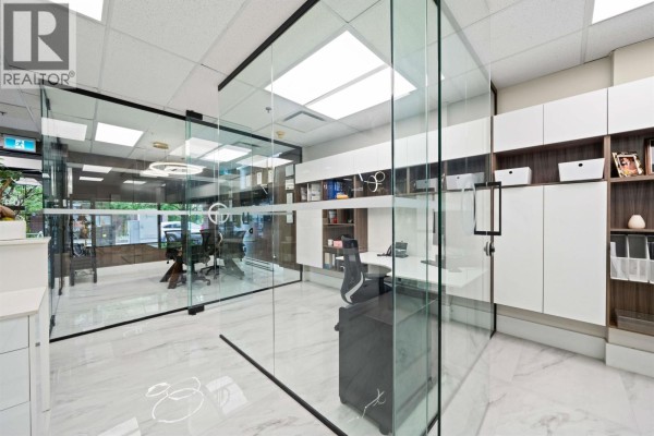 Reception desk area with wood paneling, a computer, and a glass partition. - 104 E 3rd Street, North Vancouver