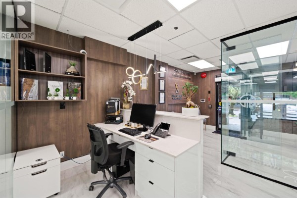 Office interior featuring a conference table, chairs, glass partitions, and modern lighting. - 104 E 3rd Street, North Vancouver