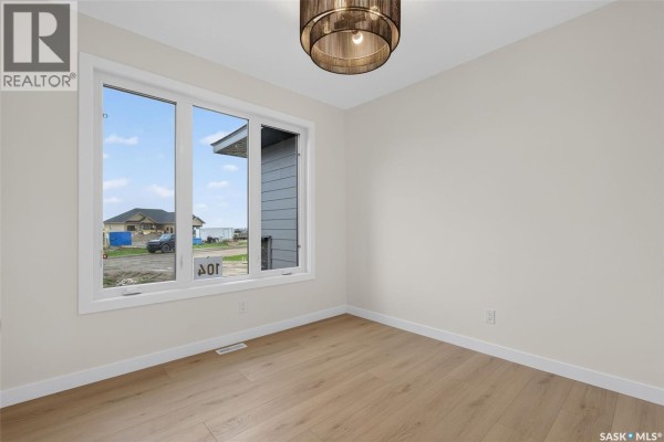 Empty room with light wood floors, a large window overlooking a new construction neighborhood. - 104 Lakewood Drive, Humboldt
