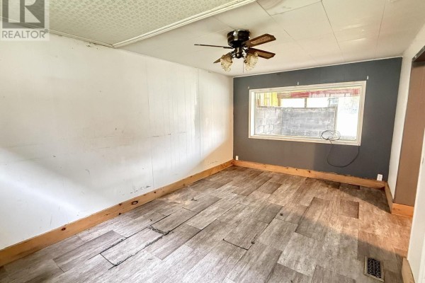 Empty room with light wood-look flooring, white paneled walls, and a dark grey accent wall. - 104 Ontario Street, Burk S Falls