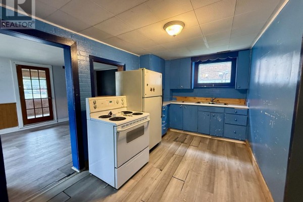 Bright blue kitchen with white appliances, wooden countertops, and a doorway leading to another room. - 104 Ontario Street, Burk S Falls
