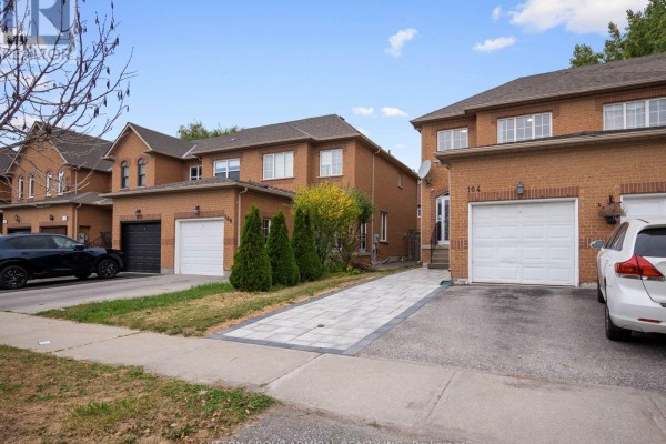 Street view of brick townhouses with garages and driveways on a paved street. - 104 Parktree Drive, Vaughan