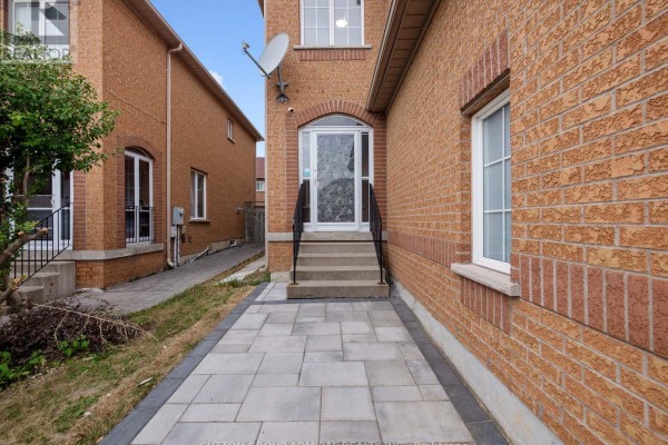 Side view of townhouse entrance with paved walkway, stairs, and brick exterior. - 104 Parktree Drive, Vaughan