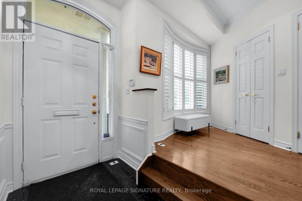 Foyer with white walls, wood floors, and a large white door with sidelight. - 104 Pleasant Boulevard, Toronto