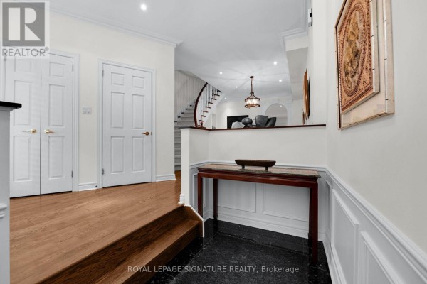Interior hallway with wood floors, white walls, wainscoting, and a curved staircase. - 104 Pleasant Boulevard, Toronto