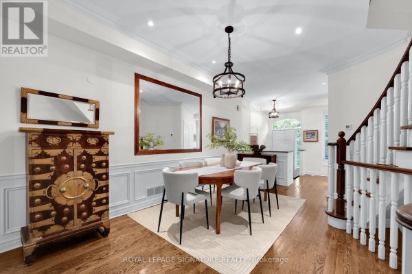 Dining room with wood table, white chairs, large mirror, and chandelier. - 104 Pleasant Boulevard, Toronto