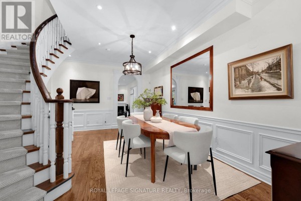 Dining room with wood floors, white chairs, and a curved staircase with white banister. - 104 Pleasant Boulevard, Toronto