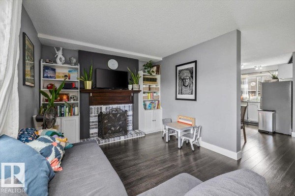Living room fireplace with a wooden mantel, brick surround, and built-in white bookshelves on either side. - 1040 Lakewood Rd N Nw Nw, Edmonton