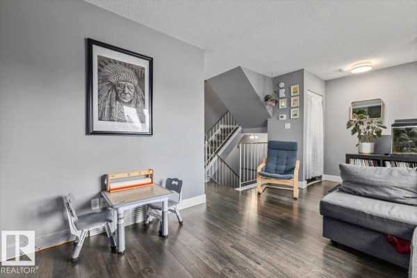 Interior view of a living room with a sectional sofa, a child's table and chairs, and a staircase. - 1040 Lakewood Rd N Nw Nw, Edmonton
