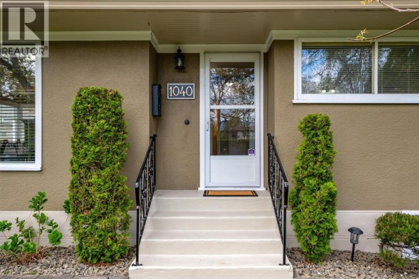 Entrance to the house with a white door, steps, and flanking decorative shrubs. - 1040 Laurier Avenue, Kelowna