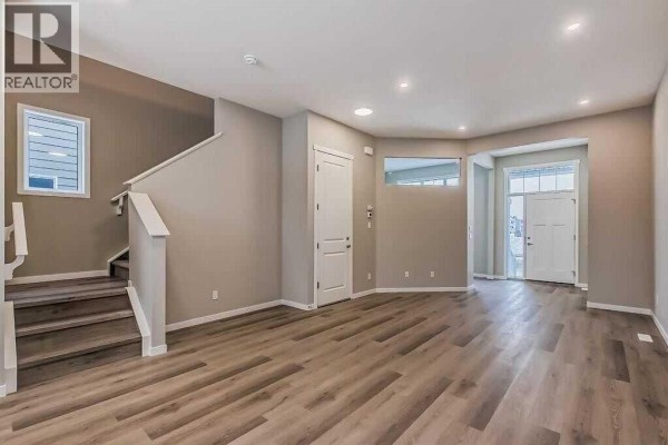 Living area with grey walls, wood-look flooring, stairs, and entryway view. - 1040 Mahogany Boulevard Se, Calgary