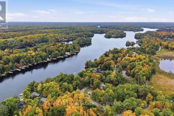 Aerial view of a wide, dark lake bordered by forested land with houses and docks. - 1040 River Street, Muskoka Lakes