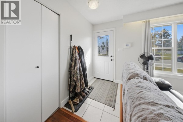 Entryway with white door, coat rack, tiled floor, and large closet. - 10404 112 Avenue, Fort St  John