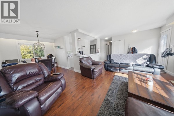Living room with leather furniture, hardwood floors, and open concept to dining and kitchen. - 10404 112 Avenue, Fort St  John