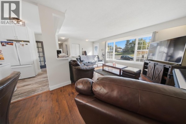 Living room with large bay window, television, and open access to kitchen. - 10404 112 Avenue, Fort St  John