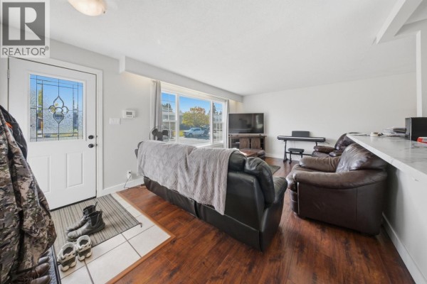 View from living room showing entryway, large window, and furniture arrangement. - 10404 112 Avenue, Fort St  John