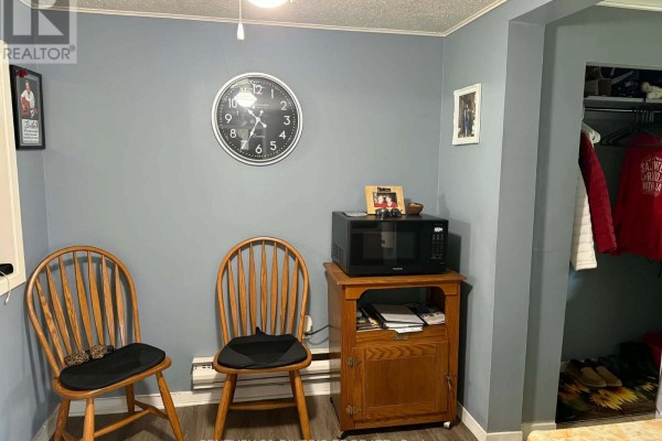 Small dining area with two wooden chairs, a microwave on a cabinet, and a clock on the wall. - 10407 Hainsville Road, South Dundas