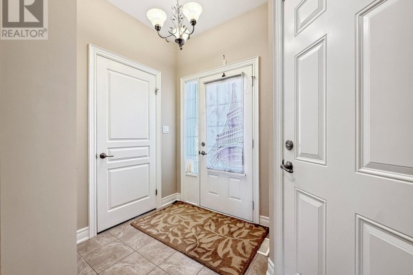 Interior view of a foyer with beige walls, tiled floors, and white doors. - 1041 Meadowood Street, Fort Erie