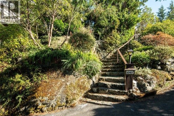 Stone steps leading up to a house entrance with a stone wall and garden. - 1043/1045 Belmont Ave, Victoria