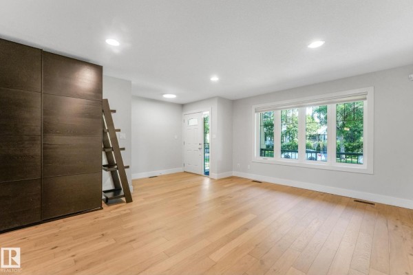 Living room featuring large windows and decorative greenery - 10433 70 Av Nw, Edmonton