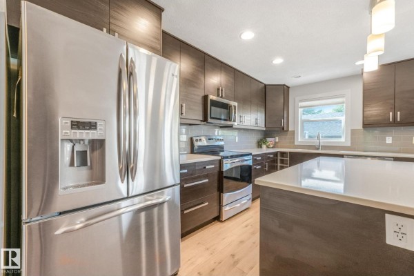 Modern kitchen with dark cabinetry, stainless steel appliances, and island - 10433 70 Av Nw, Edmonton