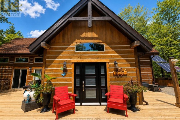 Open-concept living space with exposed wooden beams, kitchen, dining, and seating areas. - 1045 Carnahan Lane, Frontenac