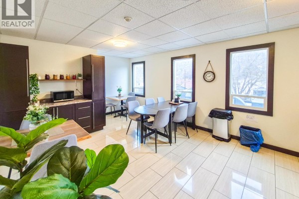 Interior dining area with a large table, grey chairs, dark wood cabinetry, and tile flooring. - 1045 Highway 97, Okanagan Falls