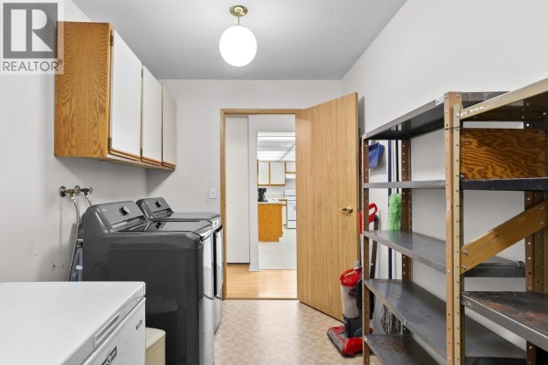 Laundry room view with appliances, storage shelves, and an open door to another room. - 1045 Sutherland Avenue Unit# 214, Kelowna