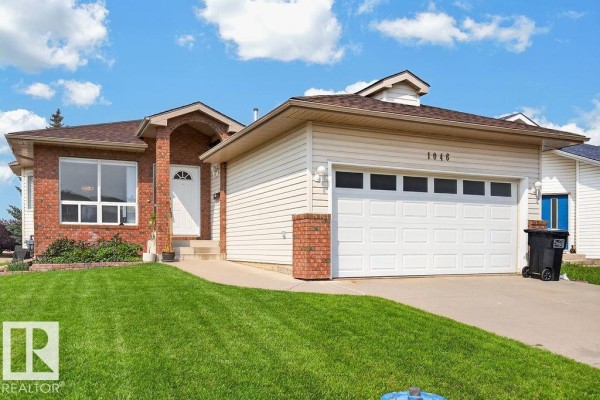 Close-up of the front entrance and garage door of a beige and brick house. - 1046 Jones Cr Nw, Edmonton