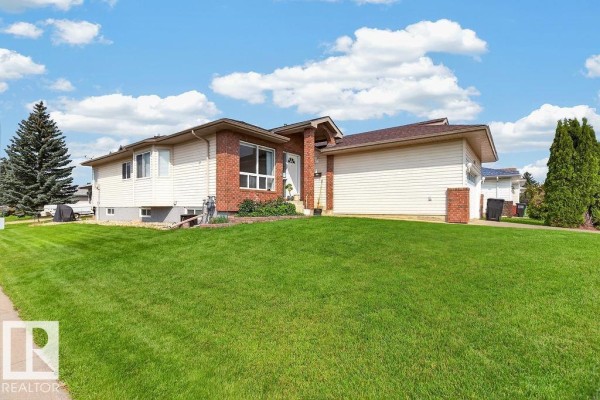 Side view of the residential property showing the lawn, brick, and siding. - 1046 Jones Cr Nw, Edmonton