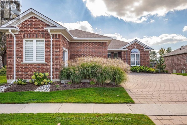Side view of a brick house with manicured landscaping and a paved driveway. - 1048 Sandy Somerville Drive, London South