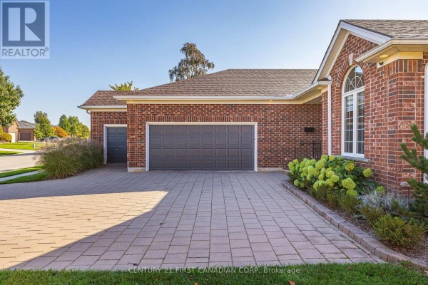 Three-car garage with dark grey doors and a paved driveway. - 1048 Sandy Somerville Drive, London South