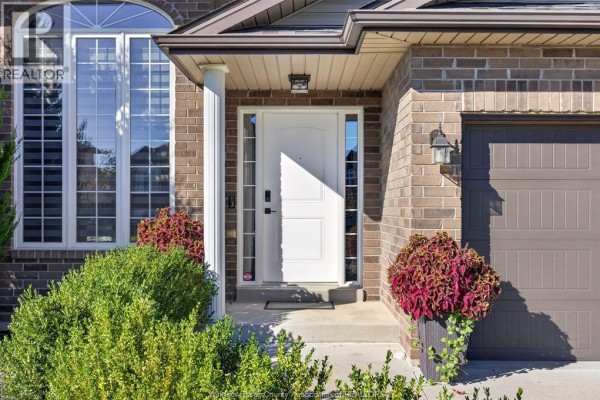 Front door with sidelight windows, white columns, and brick exterior details. - 1049 Thunderbay, Windsor
