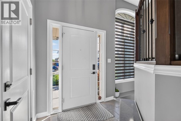 Interior view of a house entrance with a white door, gray walls, and a large arched window. - 1049 Thunderbay, Windsor