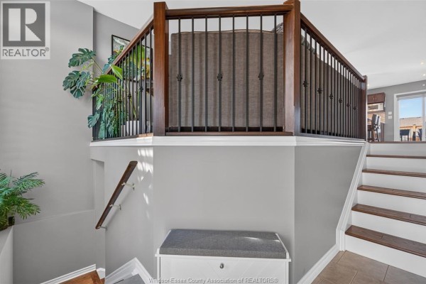 Interior view of a house interior with a staircase, bench, and open railing overlooking a living area. - 1049 Thunderbay, Windsor