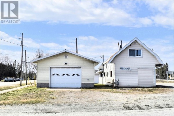 Attached garage with a white overhead door and a separate residential structure with white siding. - 10494 & 10496 Highway 17, West Nipissing