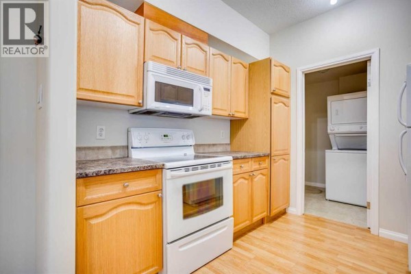 Kitchen with light wood cabinets, white stove, microwave, and patterned countertops. - 105, 290 Plamondon Drive, Fort Mcmurray