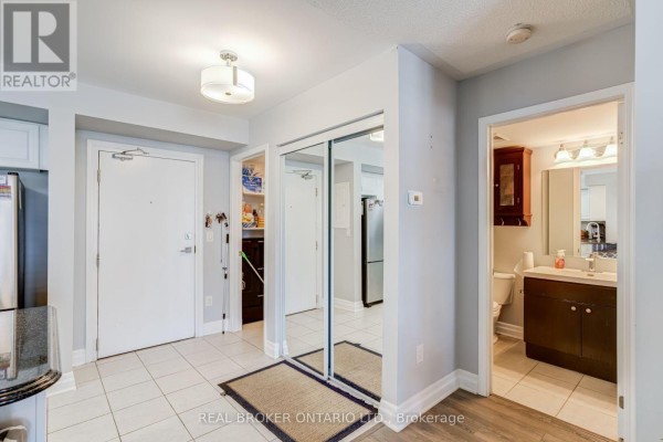 Apartment entryway with a white door, mirrored closet doors, and a doorway to a bathroom. - 105 - 1045 Nadalin Heights, Milton